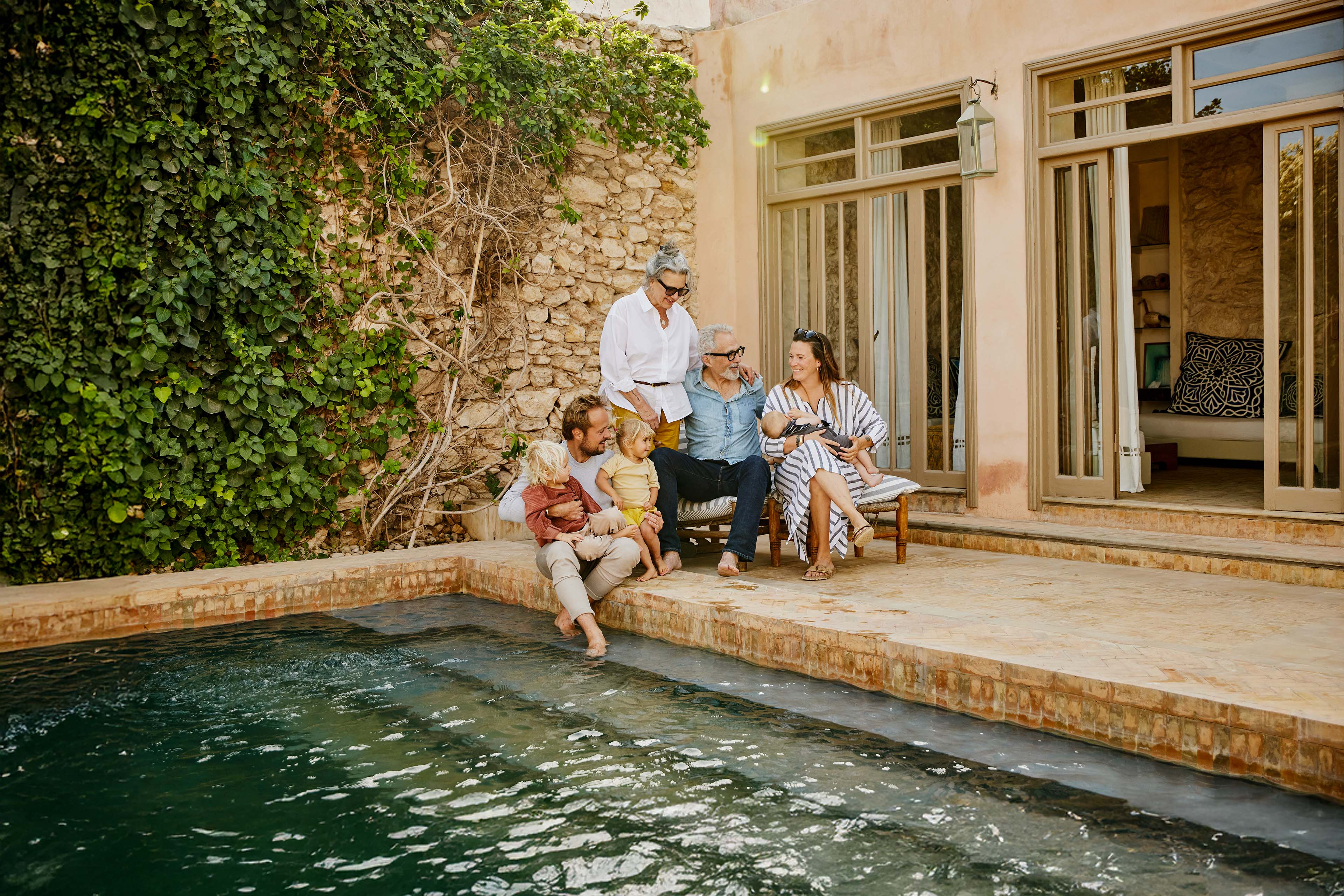 Wide shot smiling multigenerational family relaxing at tropical villa
